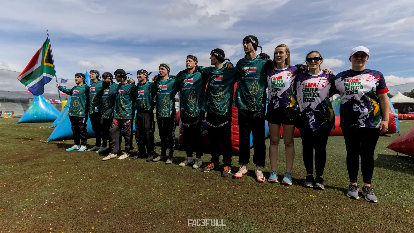South African team and staff lined up on the field beside the flag