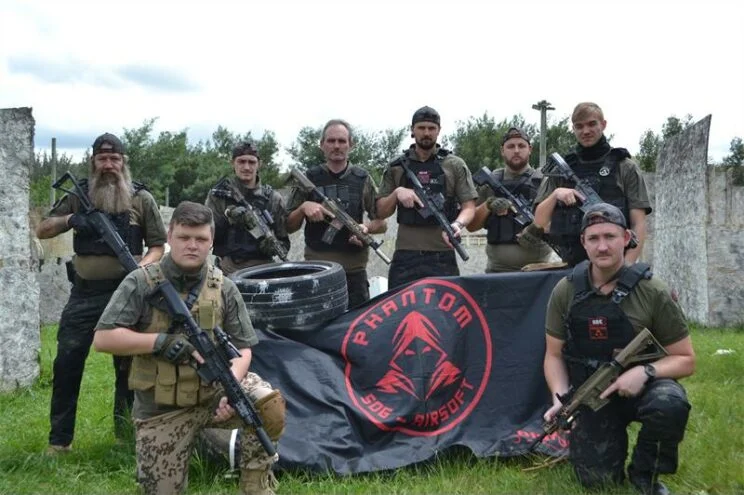 Airsoft team posing with their flag on a field