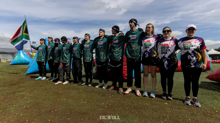 South African team and staff lined up on the field beside the flag